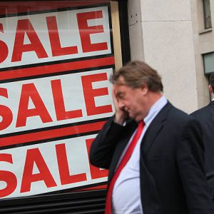LONDON, ENGLAND - SEPTEMBER 22:  A city worker rubs his face as he walks past a shop advertising a sale on September 22, 2011 in London, England. Share prices on world stock markets have fallen sharply today following several warnings over future prospects for the global economy. Both Christine Lagarde, head of the IMF and Robert Zoellick,president of the World Bank, have voiced their concerns over the health of the economic situation. Today the UK FTSE 100 has fallen 4.7%, whilst the US Dow Jones is trading at nearly 3.5% down.  (Photo by Oli Scarff/Getty Images)