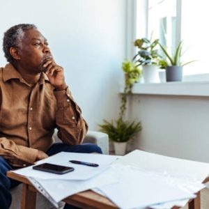 Depressed Senior Adult Man With Stacks of Papers and Envelopes